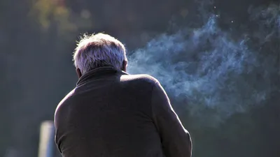 Человек курит, дым от сигареты