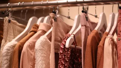 Одежда на вешалках в магазине, товары легкой промышленности